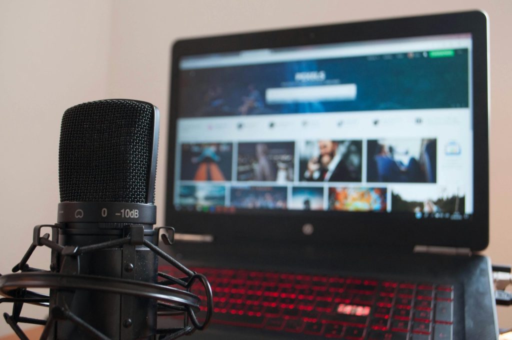 Nahaufnahme eines Mikrofons und eines Laptops auf einem Schreibtisch – geeignet für Home-Recording oder Podcasting.